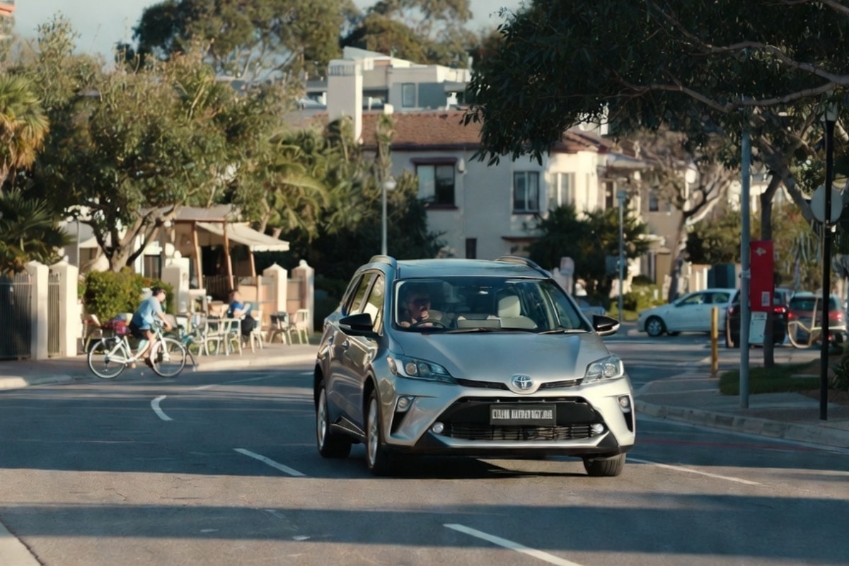 Toyota hybrid vehicle driving through a leafy suburban street in White Gum Valley for eco car rental in White Gum Valley